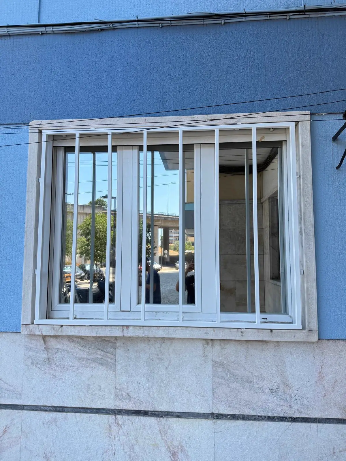 Grades de segurança brancas instaladas numa janela com peitoril em mármore